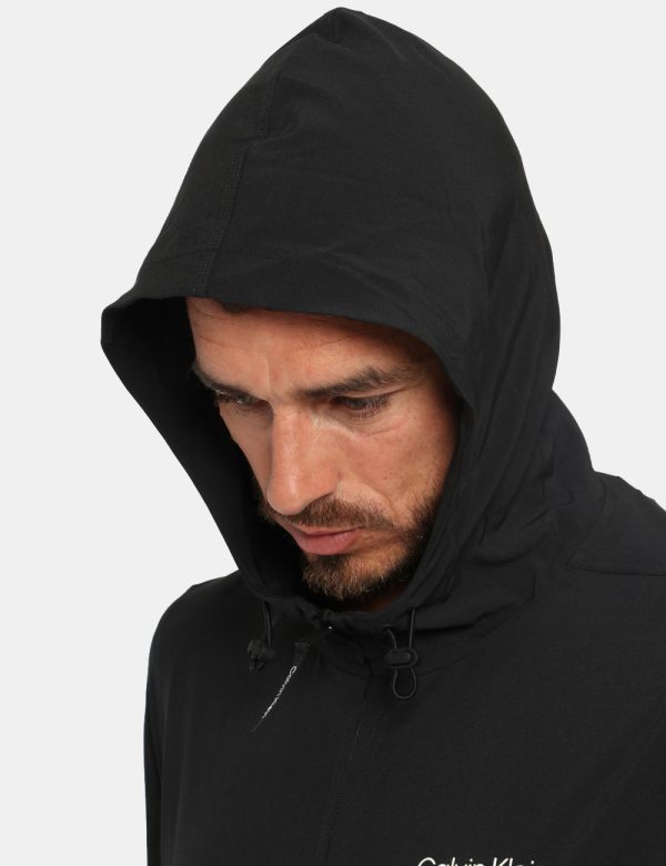Giacca Calvin Klein Nero - Giacca leggera in total nero con cappuccio. Presenti tasche a taglio trasversale più logo brand b