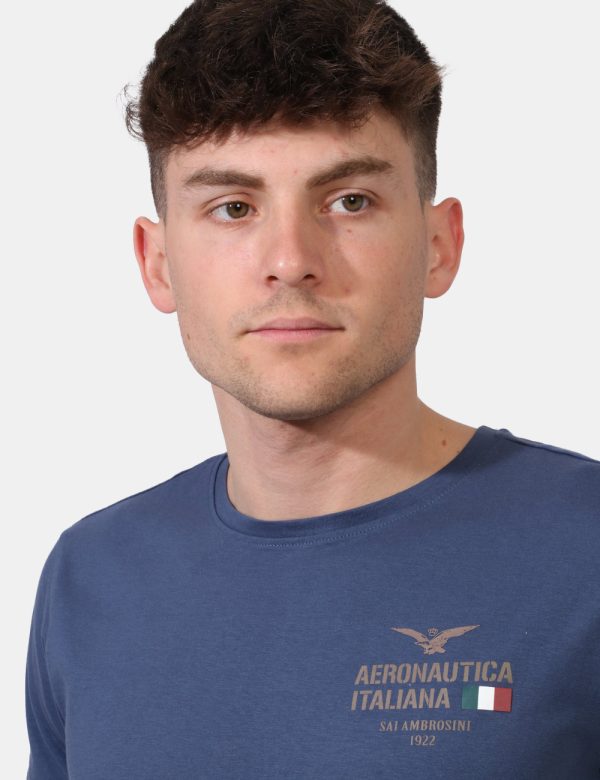 T-shirt Aeronautica Italiana Blu - T-shirt su sfondo blu slavato con stampa logo brand ad altezza cuore. La vestibilità è mo
