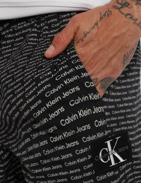 Bermuda Calvin Klein Nero - Bermuda su base nera con stampa allover logo brand bianco. Presenti tasche a taglio trasversale