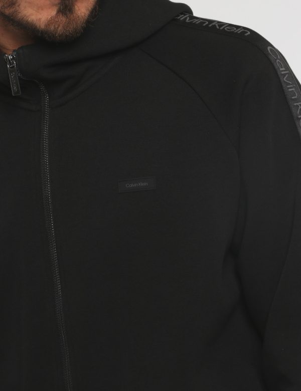 Felpa Calvin Klein Nero - Felpa a collo alto con cappuccio in total nero. Presenti tasche a taglio trasversale. La vestibil