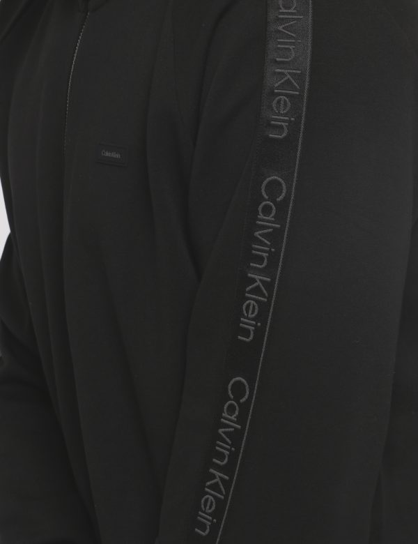 Felpa Calvin Klein Nero - Felpa a collo alto con cappuccio in total nero. Presenti tasche a taglio trasversale. La vestibil