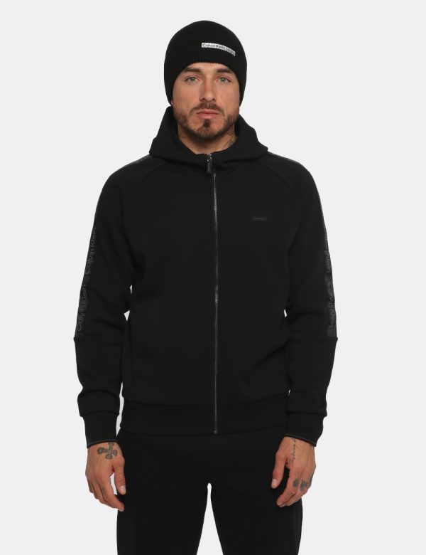Felpa Calvin Klein Nero - Felpa a collo alto con cappuccio in total nero. Presenti tasche a taglio trasversale. La vestibil