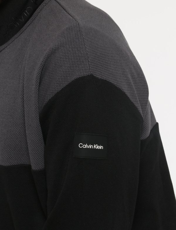 Felpa Calvin Klein Nero - Felpa a collo alto su sfondo nero e grigio traforato. La vestibilità è morbida e pratica grazie a