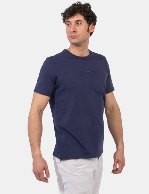 T-shirt Guess Blu - T-shirt in total blu navy con logo brand ricamato in tono su tono. La vestibilità è morbida e regolare.