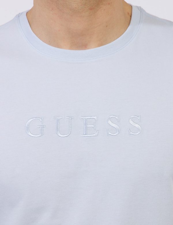 T-shirt Guess Azzurro - T-shirt in total azzurro pastello con logo brand ricamato in tono su tono. La vestibilità è morbida