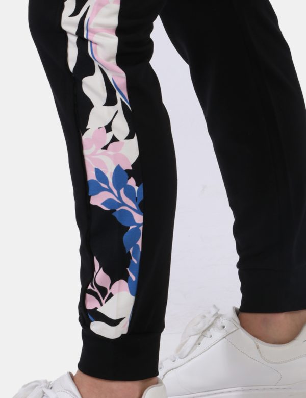 Pantaloni Liu-Jo Nero - Pantaloni tuta in total nero con bande laterali floreali in tinta tendente al rosa. Presenti tasche