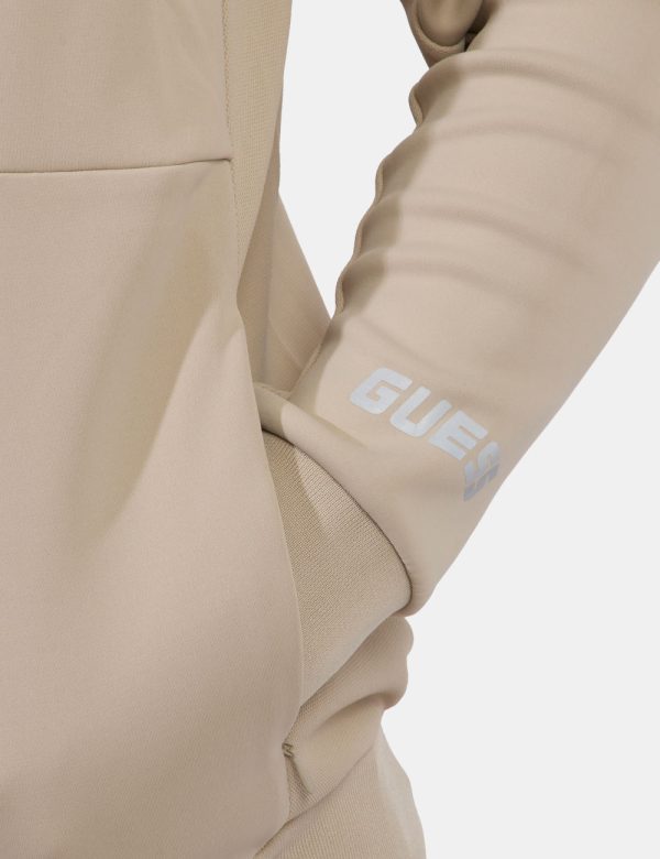 Felpa Guess Beige - Felpa in total beige con stampa logo brand sagomato ad altezza cuore. Presenti tasche a taglio trasversa