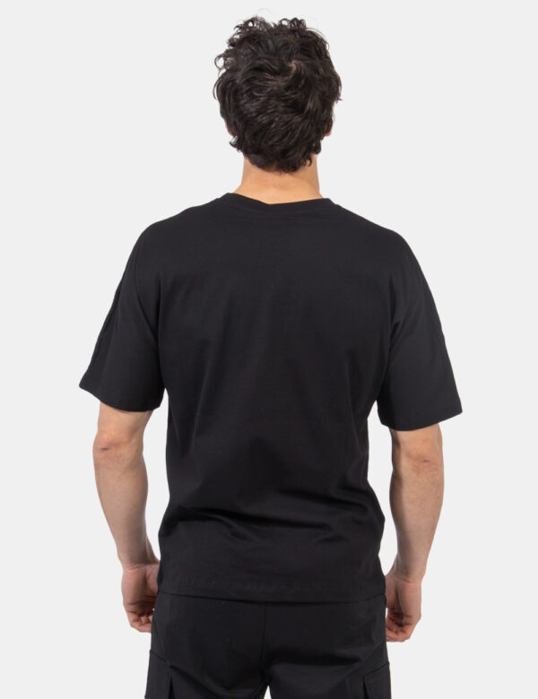 T-shirt Disclaimer Nero - T-shirt su sfondo nero con stampa logo brand nero e arancione sul fronte. La vestibilità è morbida