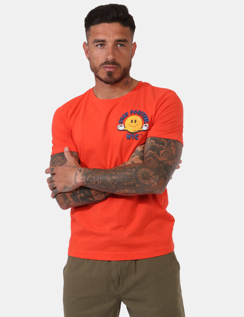 T-shirt Fred Mello Arancione - T-shirt su base arancione con stampa smile in giallo e blu. La vestibilità è morbida e regola