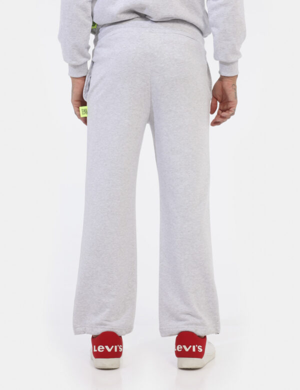 Pantaloni Icon Grigio - Pantaloni simil tuta grigio chiaro con logo brand nero. Presenti tasche a taglio trasversale. La ves