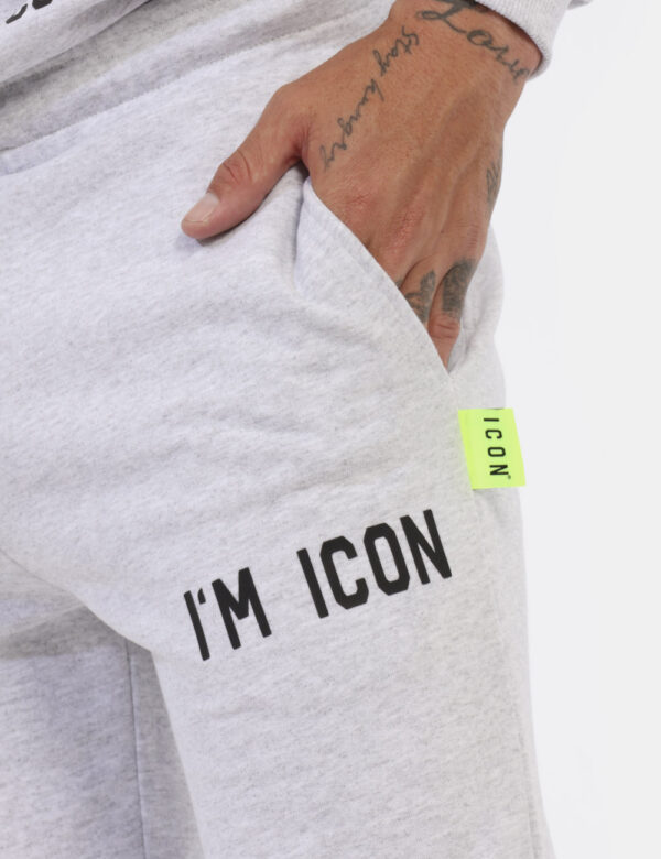Pantaloni Icon Grigio - Pantaloni simil tuta grigio chiaro con logo brand nero. Presenti tasche a taglio trasversale. La ves