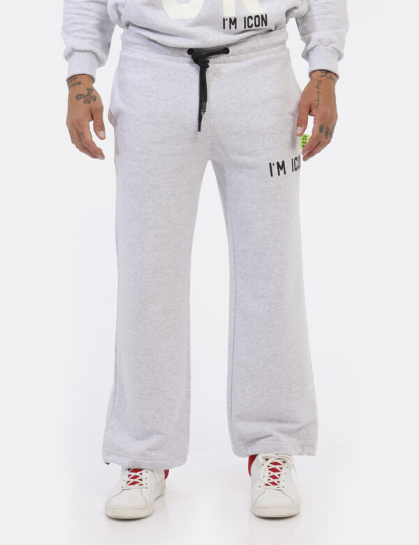 Pantaloni Icon Grigio - Pantaloni simil tuta grigio chiaro con logo brand nero. Presenti tasche a taglio trasversale. La ves