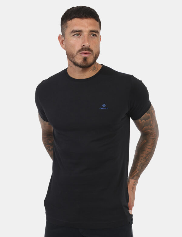 T-Shirt Gant Nero - T-shirt classica in total nero con patch logo brand ad altezza cuore in blu. La vestibilità è morbida e