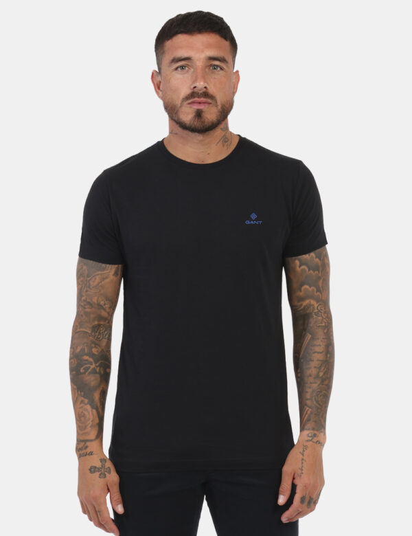 T-Shirt Gant Nero - T-shirt classica in total nero con patch logo brand ad altezza cuore in blu. La vestibilità è morbida e