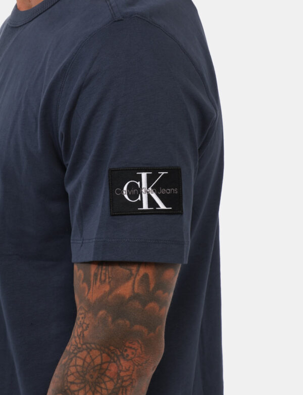 T-shirt Calvin Klein Blu - T-shirt classica in total blu navy con patch logo brand sulla manica sinistra. La vestibilità è m