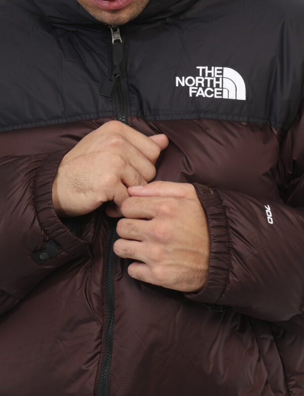 Piumino The North Face Marrone - Piumino bicolor marrone e nero con cappuccio interno. Presenti tasche a taglio trasversale