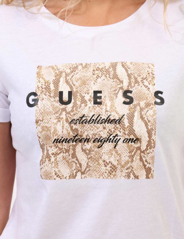 T-shirt Guess Bianco - T-shirt classica su base bianca con stampa logo brand in nero arricchita da glitter dorati. La vestib