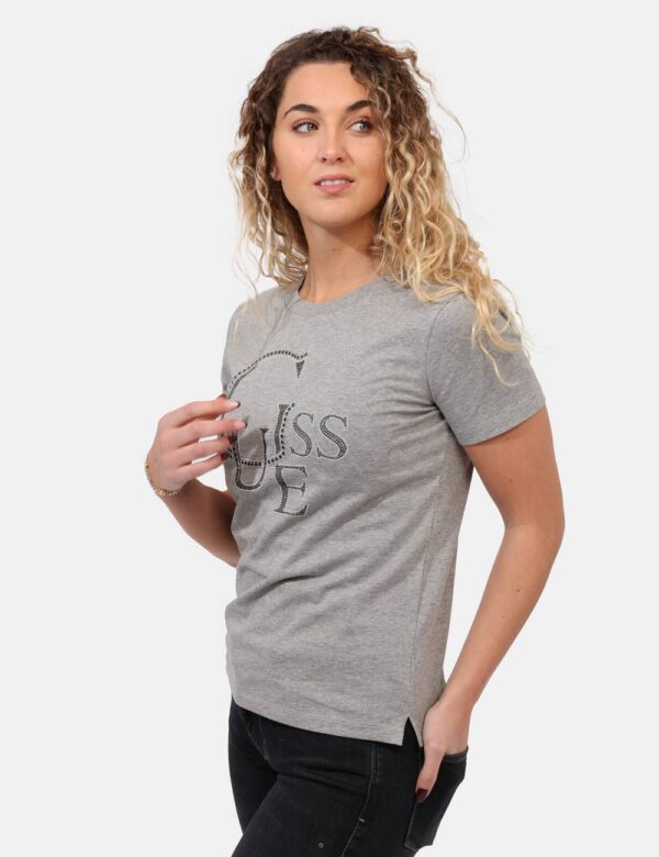 T-shirt Guess Grigio - T-shirt classica su base grigio chiaro con stampa centrale logo brand in glitter argentati. La vestib
