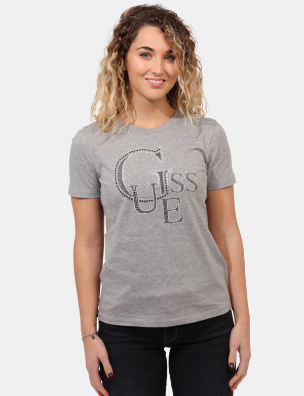 T-shirt Guess Grigio - T-shirt classica su base grigio chiaro con stampa centrale logo brand in glitter argentati. La vestib