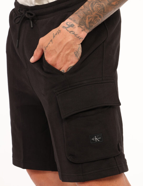Bermuda Calvin Klein Nero - Bermuda in tessuto ed in total nero, con tasche a taglio trasversale e tasche cargo laterali. La