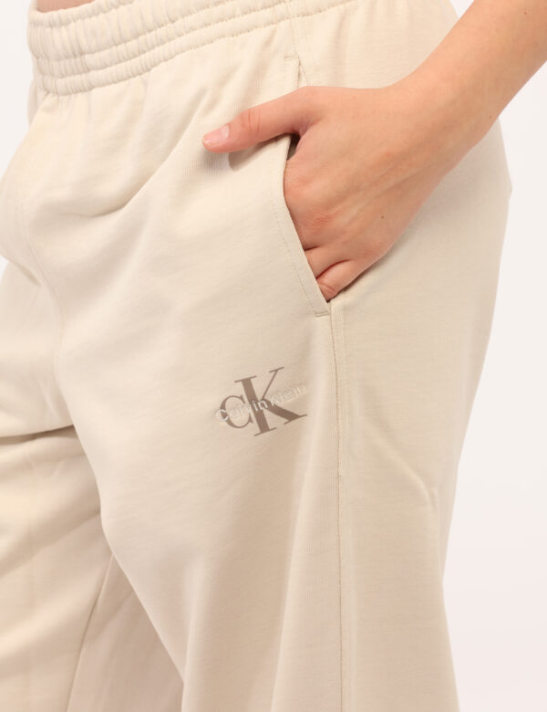 Pantaloni Calvin Klein Beige - Pantaloni tuta in total beige, con logo brand ricamato bianco e tasche a taglio trasversale.