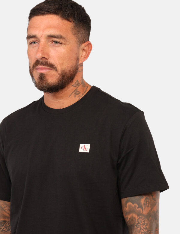 T-shirt Calvin Klein Nero - T-shirt classica in total nero con patch logo brand nero. La vestibilità è morbida e regolare. L
