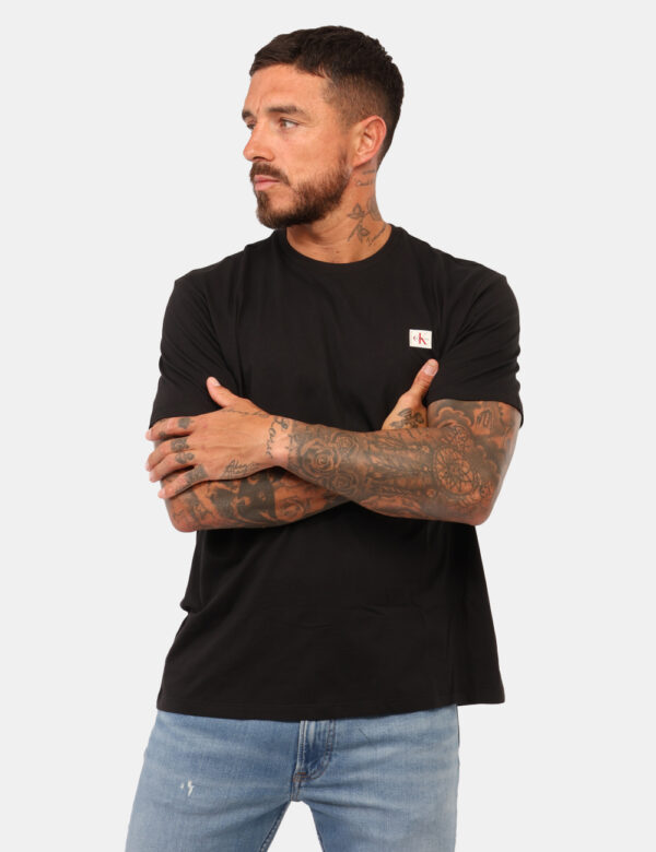 T-shirt Calvin Klein Nero - T-shirt classica in total nero con patch logo brand nero. La vestibilità è morbida e regolare. L