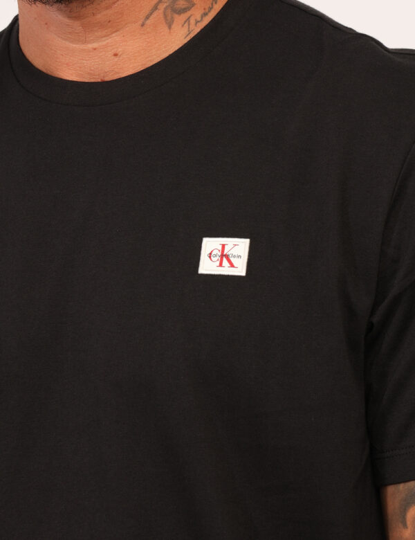 T-shirt Calvin Klein Nero - T-shirt classica in total nero con patch logo brand nero. La vestibilità è morbida e regolare. L