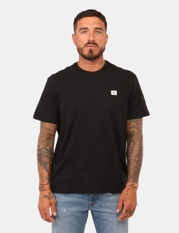T-shirt Calvin Klein Nero - T-shirt classica in total nero con patch logo brand nero. La vestibilità è morbida e regolare. L