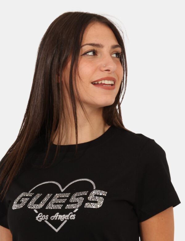 T-shirt Guess Nero - T-shirt classica su base nero con stampa logo brand in glitter argentati. La vestibilità è morbida e re