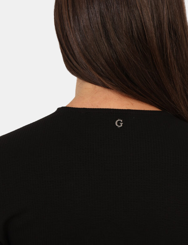Maglia Guess Nero - Maglia costina a maniche lunghe in total nero, con bottoncini sui polsini. La vestibilità è morbida e re