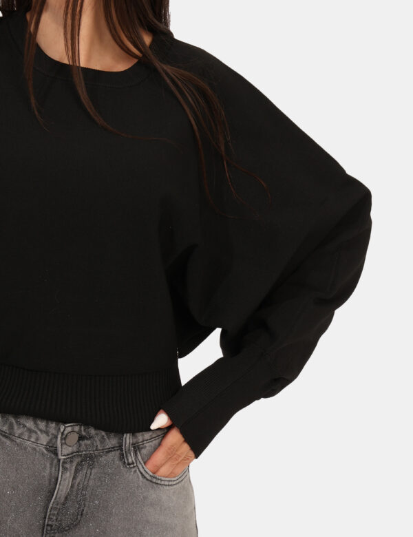 Maglione Guess Nero - Maglione corto, in total nero con girocollo classico e polsini. La vestibilità è morbida e regolare. L